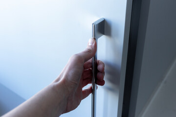 A hand opening a closet door.