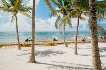 Paradise beach Akumal on the Caribbean coast of the Gulf of Mexico. White sand, palm trees and wood boats. Mexico, Riviera Maya