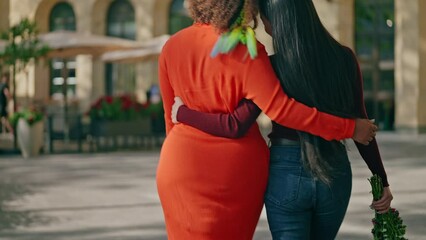 Back view of happy multiethnic lesbian couple walking on street, romantic date