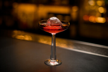 selective focus of beautiful wine glass with ice and drink on bar