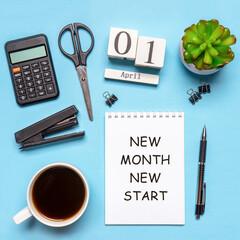 Office workplace with coffee cup, calculator, stationery and plant. Date 01 April on wooden block calendar. Text NEW MONTH NEW START on white notepad page. Table desk top view, flat lay