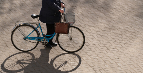 an old woman walks down the street with a bicycle and bags