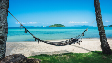 Fototapeta premium Relax beach hammock on peaceful white sand beach tropical island with clear turquoise sea against blue sky with Koh Kham view at horizon. Koh Mak Island, Trat, Thailand.