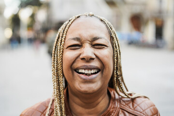 Senior african woman smiling on camera with city on background - Focus on mouth