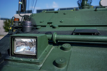 Armoured vehicle front green steel plating, close-up detail to small head light