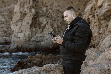 Young man operating a drone over the sea