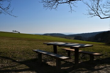 Fototapeta na wymiar Bänke mit Tisch / Rastplatz auf grünen Feldern im Sonnenlicht