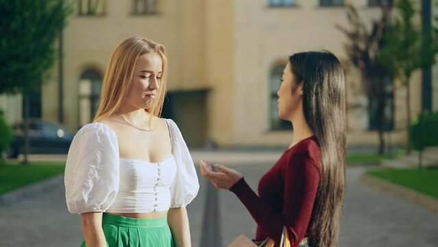 Asian woman criticizing blond friend outfit, envy and friendship, insecurities