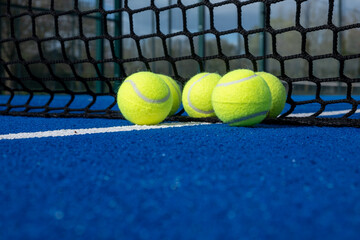 selective focus, five paddle tennis balls near the net of a blue paddle tennis court