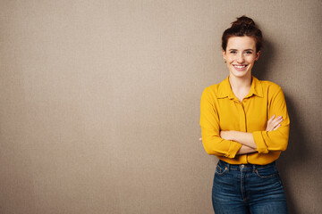 young smiling business woman with yellow blouse stands in front of brown background - 495079019