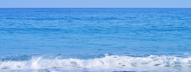 Seascape blue wallpaper - panoramic view on beach with white foam of surf, blue waves of water, horizon and sky