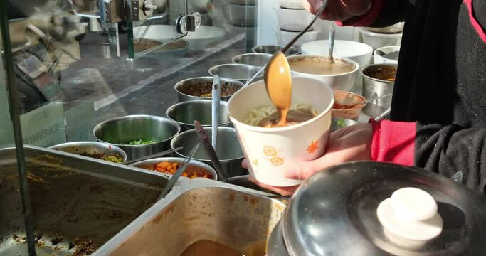 making Hot dry noodles. Traditional food in Wuhan, Hubei, China. Putting sesame paste and seasoning in noodles. Slow motion 