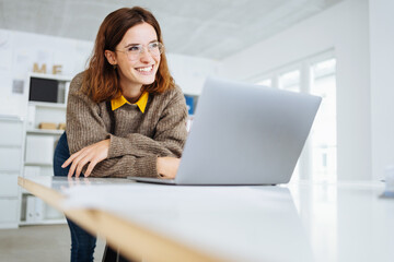young modern businesswoman leans on the desk and looks to the side laughing