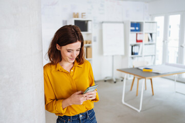 young modern business woman looking at her cell phone in office
