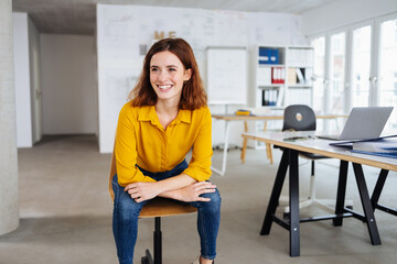 young laughing woman sits in office and looks to the side