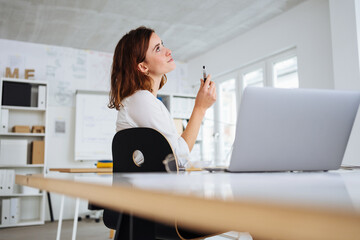 young modern thoughtful business woman sitting at desk in office
