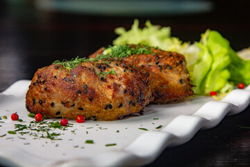 Large. Beef patties with pepper are on a plate with a green salad