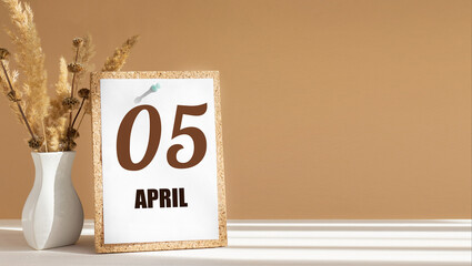 April 5. 5th day of month, calendar date.White vase with dead wood next to cork board with numbers. White-beige background with striped shadow. Concept of day of year, time planner, spring month