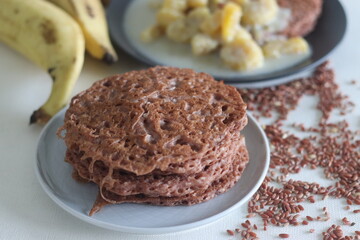 Fototapeta na wymiar Red rice pancakes. Pancakes made of a fermented batter of red rice and coconut. Served with Ripe plantain stew