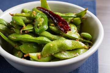 A view of a bowl of spicy edamame bean pods.