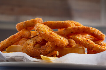 A view of an appetizer plate, featuring calamari rings and french fries.