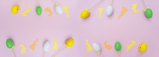 Top view photo of easter decorations easter bunnies yellow and beige and easter eggs on isolated pastel pink background with copyspace. Easter composition for the cover.