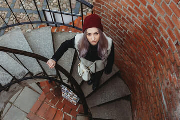 Beautiful young woman standing on spiral staircase