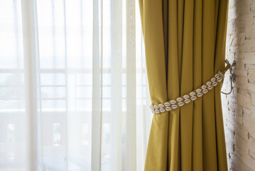 Beautiful yellow curtain shell decoration in resort interior room with sunlight. Interior decoration concept. 