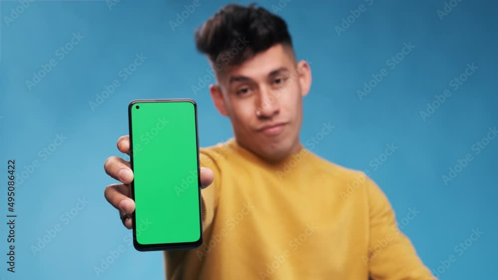 Poster man showing a smartphone with green screen while standing over an isolated background.