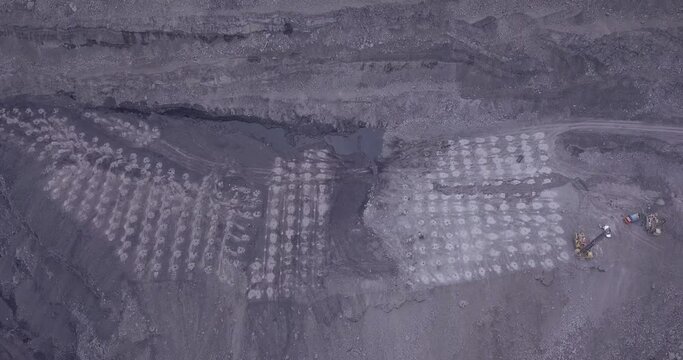 Aerial view of blasting holes coal mining area, open-pit mine, quarrying.  Drone shooting preparing for blasting open cast mine mining of coal, overall plan.