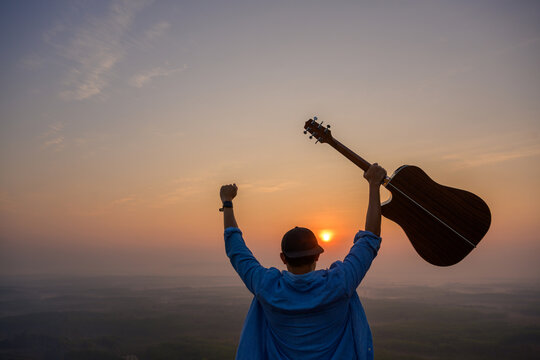 Tourist and male musician holding classical acoustic guitar Wake up to the mountain early to watch the sunrise. glad you succeeded Beautiful natural style of forests and mountains in Thailand. - Powered by Adobe