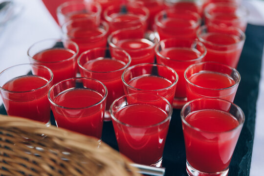 Small glasses filled with red colored liquid - drink with watercolor juice. Catering buffet serving food.
