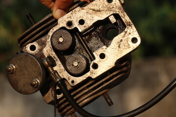 The cylinder head of an old diesel engine disassembled held in hand for repairing with a view of fuel inlets and its cooling fins