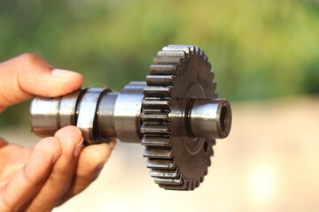 Camshaft sprocket of internal combustion engine held in hand isolated on nature background