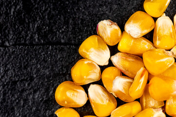 Corn grains on the black, stone background.  Object lit with a uniform, soft light.