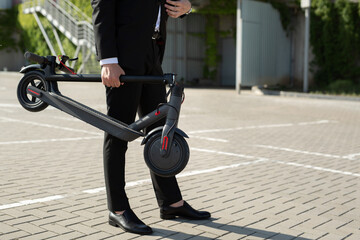 Close-up of a businessman's hands with an electric scooter © Studio Peace
