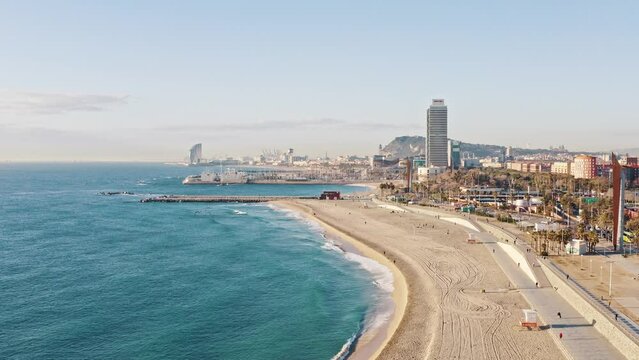 Panoramic aerial scenery of turquoise Mediterranean sea waves falling on Golden Beach shore at Barcelona, Spain. Sandy cost of beautiful bay neighboring with urban landscape tall buildings of big city