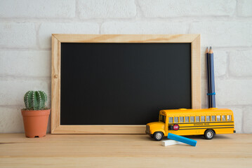Black to school education concept. Blank blackboard and school bus model, pencil on wooden table...
