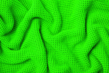 Knitted surface of woolen things as a background. Close-up of soft fabric green color knitted patterns texture. Warm winter clothing. Background textile surface with copy space for text.