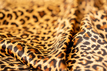 Satin fabric close up background and texture with place for text. Leopard print, silk orange.