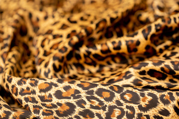 Satin fabric close up background and texture with place for text. Leopard print, silk orange.