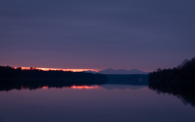 Fototapeta na wymiar Calm nightfall over Sava river with fading light under clouds and mountain silhouette - natural landscape