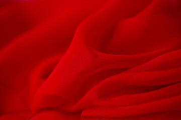 Red chiffon or silk material. Satin fabric close up background and texture with place for text. blurred background.