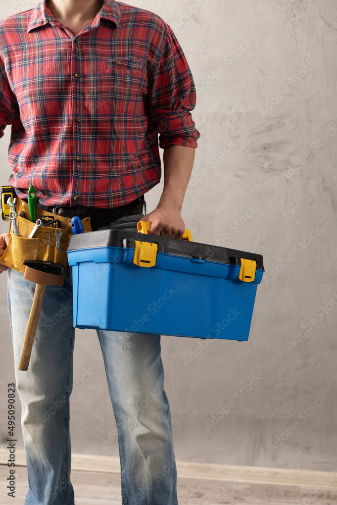 Wall mural Worker man holding construction tool box in house room renovation. Male hand and toolbox