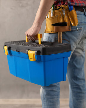 Worker man holding construction tool box in house room renovation. Male hand and toolbox