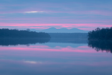 Peaceful atmospheric landscape with pastel colors, Sava river at twilight, forested banks lead to...