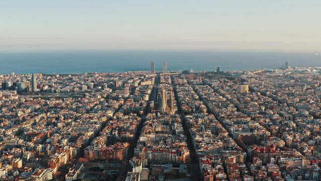 Aerial view on comfortable urban district of Barcelona, Eixample neigborhood. City blocks are separated by straight streets. Sagrada Familia cathedral is in centre of panorama, sea is on background