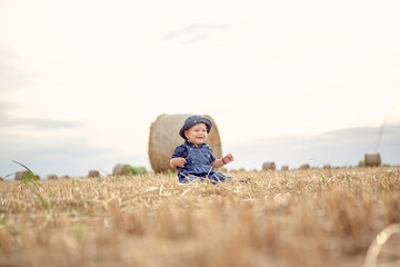 Naklejka na ściany i meble Little smiling girl on a gold wheat field.
