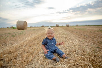  baby girl with a beautiful smile at gold wheat field.
