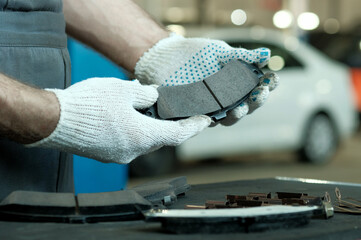 Rear brake pads. Close-up. An auto mechanic inspects a set of rear brake pads for the car. Control of compliance and integrity of spare parts. Maintenance and repair in a car service. © Jevgenyij